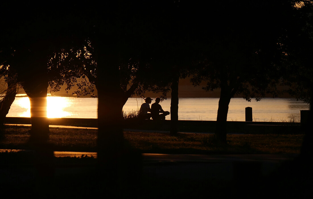 Foto 2 personen die aan het praten zijn bij een rivier